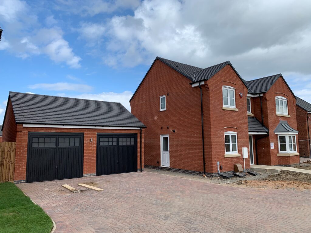 Black double garage doors on a new build house showing typical developer-grade doors.